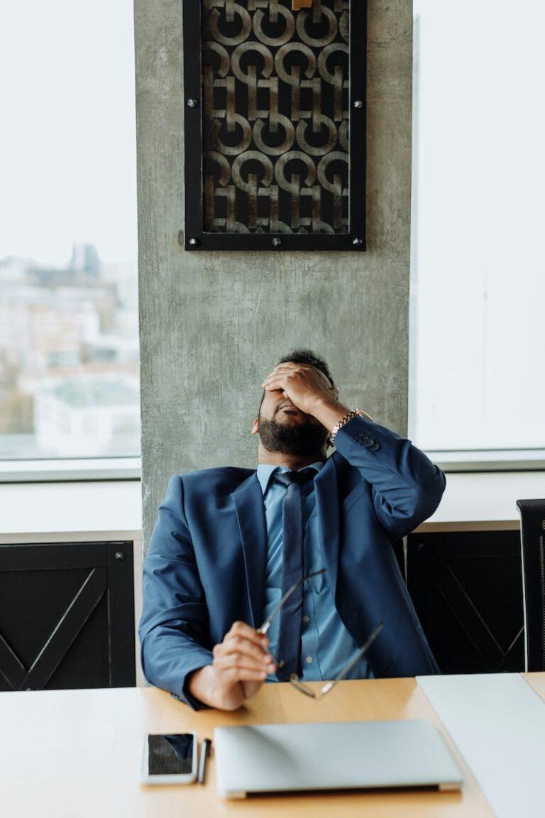 person leaning back, covering their eyes